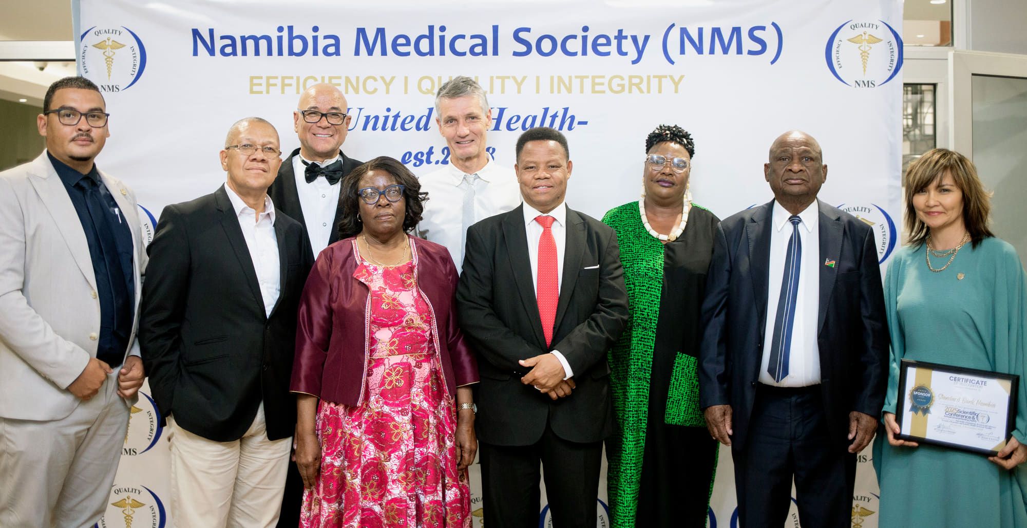 Members and guests of the Namibia Medical Society gathered before an NMS backdrop.