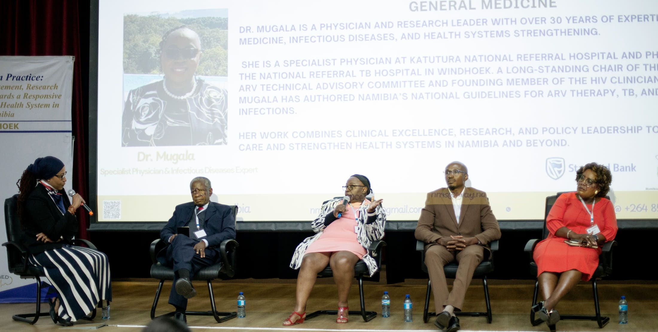 A scientific panel on stage during an NMS conference session.
